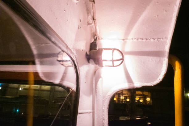istock Vintage Nautical Light Fixture Illuminating a Ship's Interior During Evening Reflecting on Glass Surface with Warm Glow and Shadows Around the Weathered Metal Structure 2188386911