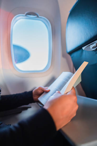 istock Relaxed Airplane Travel Experience with a Passenger Enjoying a Book by the Window, Capturing the Serenity of Journeying Through the Sky with Comfort and Leisure Reading on a Flight. 2188387853