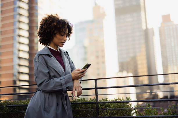 istock Businesswoman Enjoying New York View While Using Smartphone on Rooftop Terrace 2188388547