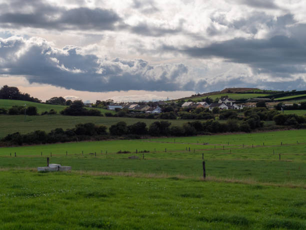 istock A Irish village among green fields and trees under a cloudy evening sky, County Cork. Rustic Irish landscape in summer, European village. Green grass field under cloudy sky 2188393572