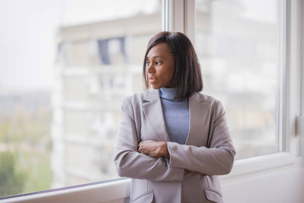 istock Business woman looking through window with hands clasped 2188393834