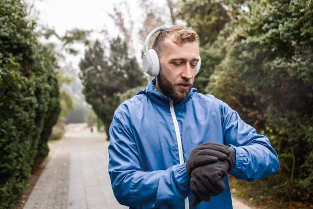 istock Headphone-Wearing Runner Resting in Misty Park Looking at Smart Watch 2188393881