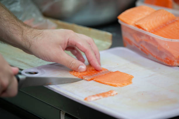 istock Human hands are slicing red fish with a knife. 2188394694