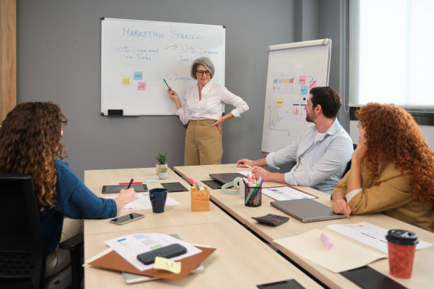 istock Marketing team meeting: senior executive explaining strategy on whiteboard 2188395585