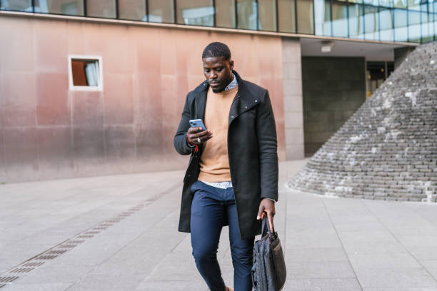 istock Businessman walking and using smartphone in urban setting 2188395975
