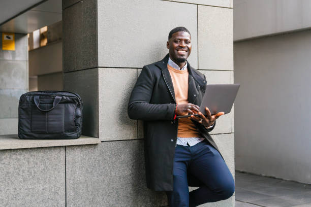 istock Smiling businessman working on laptop near office building 2188396079
