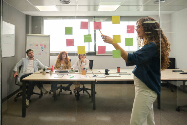 istock Young manager using sticky notes during presentation to coworkers in modern office 2188396984