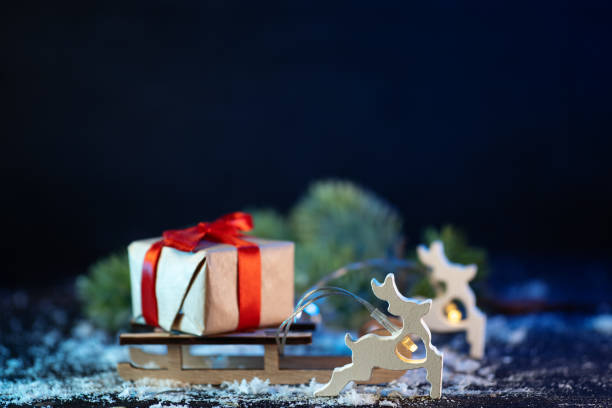 istock Toy reindeer pulling a wooden sleigh with a Christmas gift 2188397119