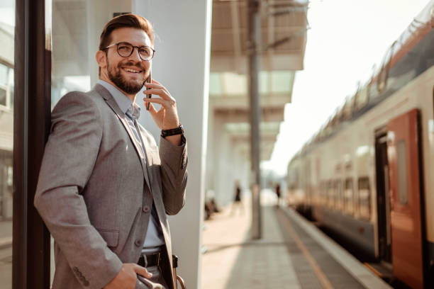 istock Business Talk: Man in Suit Handling Phone Call While Waiting for Train 2188411503