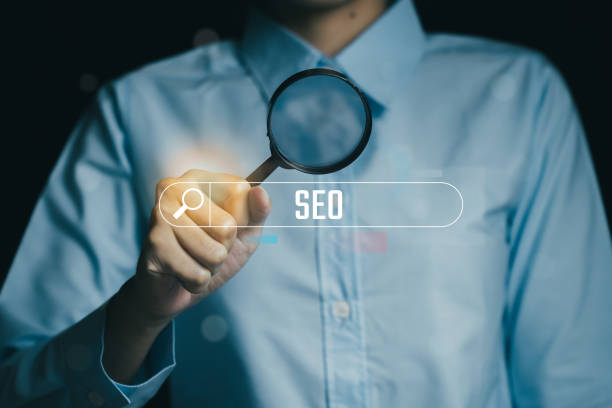 istock person holding magnifying glass over word SEO, symbolizing search optimization. image conveys sense of focus and analysis in digital marketing 2188412662
