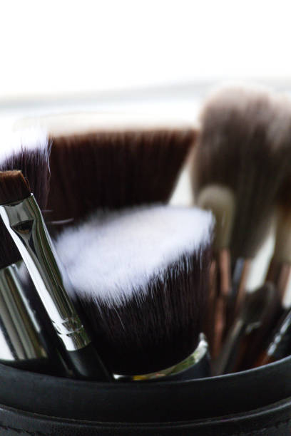 A collection of makeup brushes sits organized in a round container, displaying different shapes and sizes, ideal for both professional makeup artists and personal enthusiasts.
