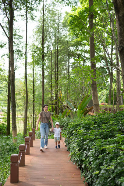 istock Mother and child walking through lush green forest path 2188414699