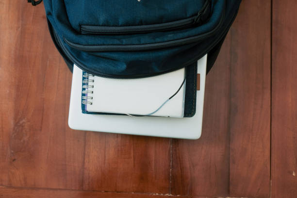 Blue backpack with books and laptop for student or working on the wooden table, concept back to school or working.