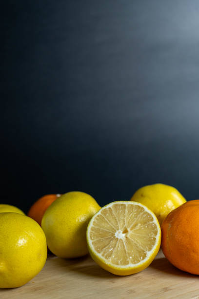 A composition of lemons and mandarins with a halved lemon in the foreground, focusing on fresh citrus fruits.