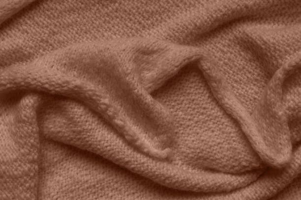 Wool fabric texture close-up background. Knitted brown, mocha sweater or scarf with folds. Top view, flat lay