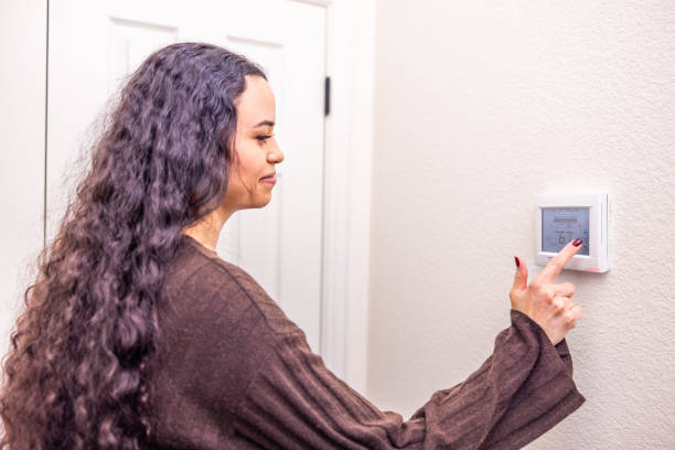 istock Young woman changing thermostat at home 2188426042