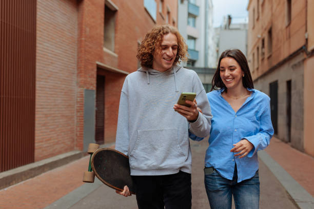istock Young couple walking and using smartphone in the city 2188427497