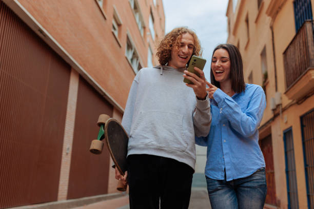istock Young couple laughing and using a smartphone while walking down the street 2188427499