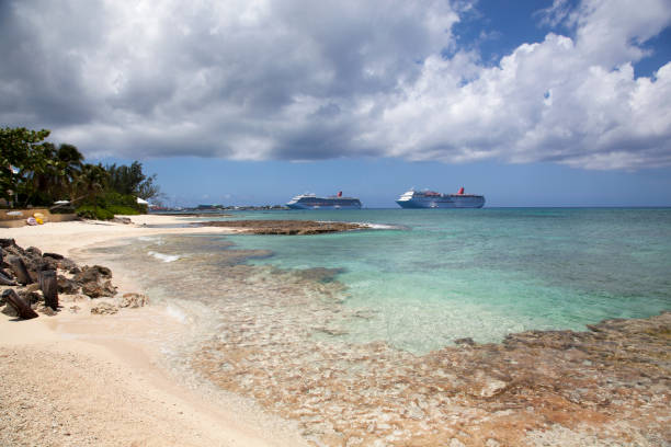 The scenic view of Grand Cayman island Seven Mile empty beach and drifting cruise ships in a background (Cayman Islands).
