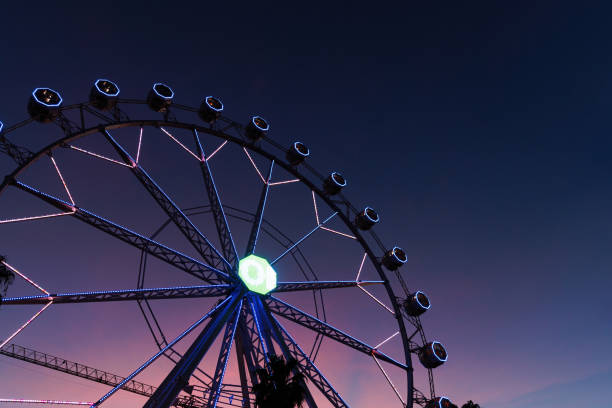 Ferris wheel with colorful lights illuminating the night sky at an amusement park, creating a magical atmosphere