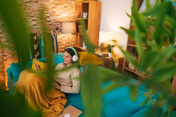 istock Woman sitting on comfy couch reading a book 2188429422