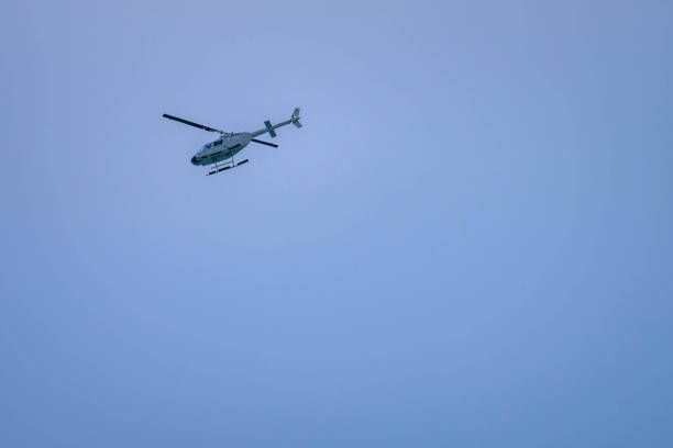 White helicopter flying in a vast, clear blue sky, conveying a sense of freedom and adventure