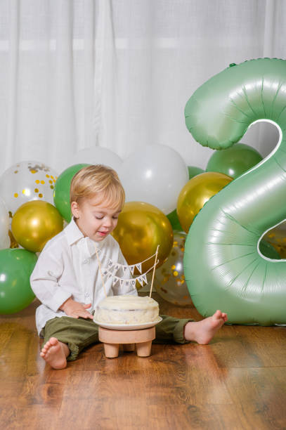 Toddler Celebrating Second Birthday with Cake and Balloons