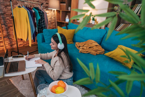 istock Young woman at home office looking at papers, holding a pen, checking her work 2188429998