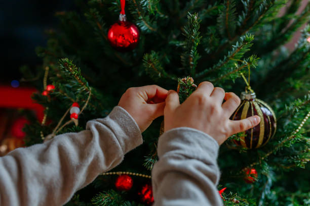 istock close up view of child hands holding christmas tree decoration putting it on tree 2188433805