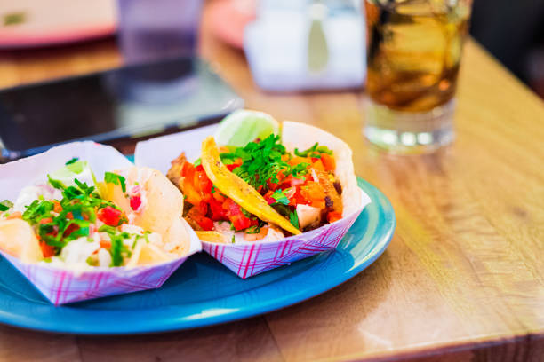 Colorful Street Tacos on a Blue Plate with Fresh Vegetables, Lime, and a Refreshing Drink Creating a Vibrant and Inviting Culinary Presentation in a Casual Dining Setting