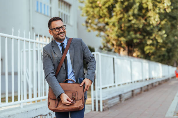 istock Smiling Businessman Walking Outdoors With Briefcase 2188441955