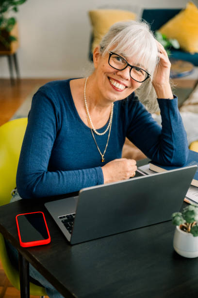 istock Senior woman working from home with laptop smiling at camera 2188443782