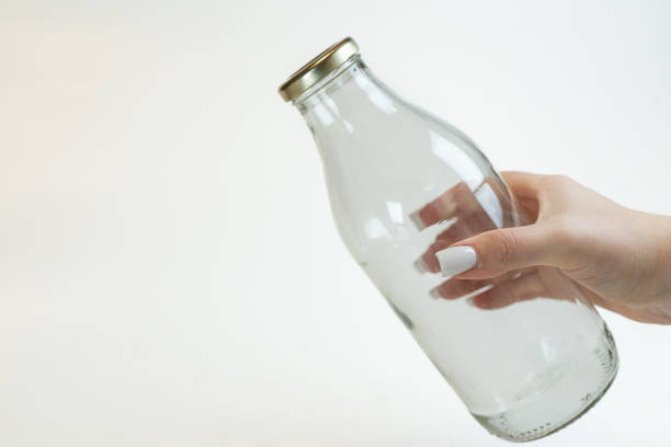 A hand holding out a clear milk bottle.