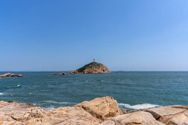 Sunny weather, reefs by the seaside and lighthouse on island
