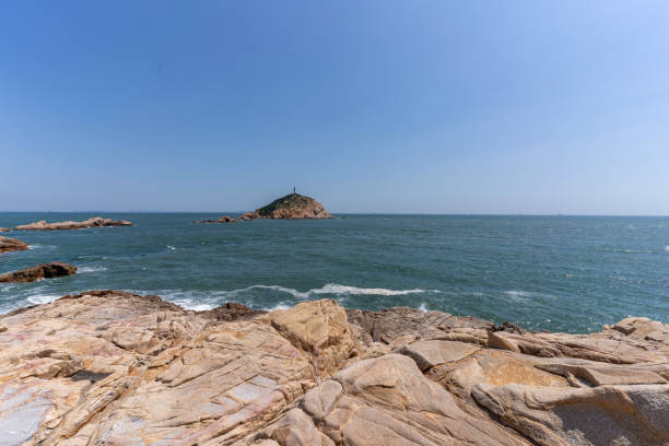 Sunny weather, reefs by the seaside and lighthouse on island