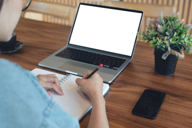 istock Young business woman sitting at table and taking note on notebook, searching teh information on laptop computer at coffee shop. Student studying online, freelance online working at coffee shop 2188456243