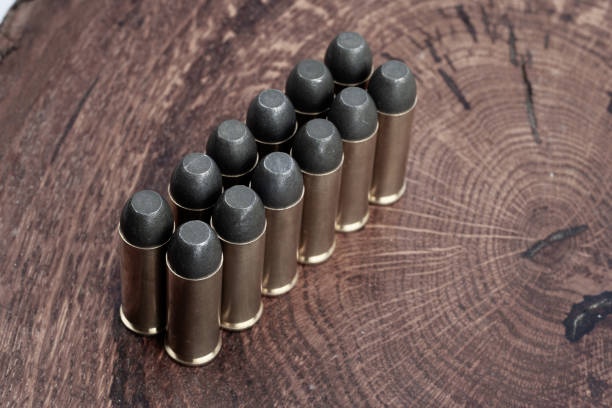 Old West era Long Colt .45 caliber revolver cartridges Old West era Long Colt .45 caliber revolver cartridges on a wooden table forty five caliber handgun stock pictures, royalty-free photos & images