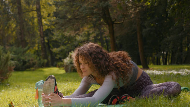 istock Sportive slim woman doing stretch warming up bend to leg knee stretching flexibility practice outdoors in summer park at mat fitness exercise workout training yoga girl at nature sporty female sport 2188465326