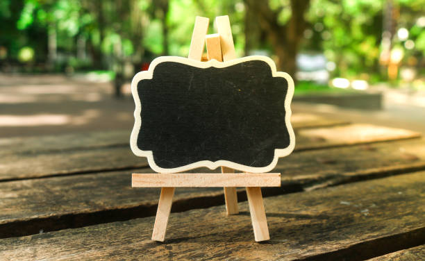 Mini blackboard with blank space for text on wooden table with garden background. Standing blank blackboard