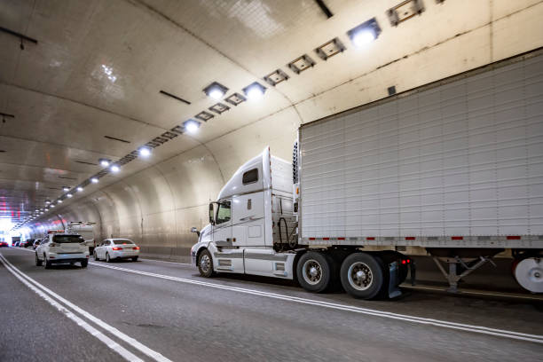 istock Bonnet big rig white semi truck transporting cargo in refrigerator semi trailer running on the one way multiline tunnel 2188476528