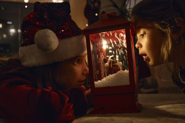 Beautiful girls on a New Year’s Eve looking at lantern with fake snow, dreaming about future.