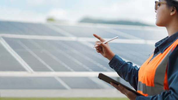 istock Female electrical engineer wearing hard hat inspecting solar farm panel equipment. Eco-friendly energy. Renewable clean energy technology concept. 2188479117