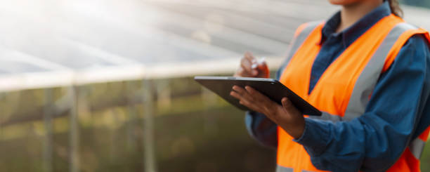 istock Female electrical engineer wearing hard hat using laptop checking solar panel farm equipment. Eco-friendly energy. Renewable clean energy technology concept. 2188479141