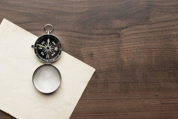 istock Compass and old paper on wooden table 2188479491