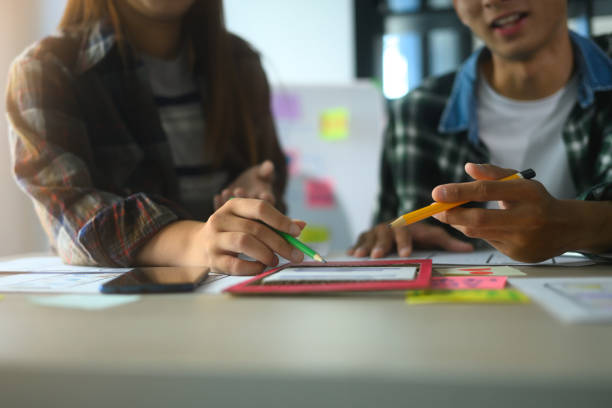 istock Close up of designers collaborating on a UX/UI project, using colorful sticky notes and wireframes 2188480930