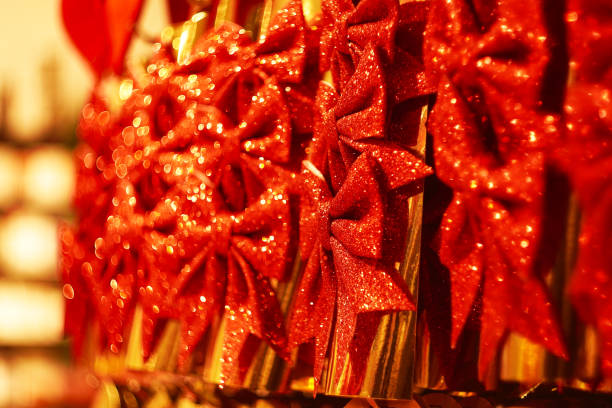 Close-up of shiny red glitter Christmas bows, warmly lit, creating a festive holiday atmosphere with rich colors and bokeh