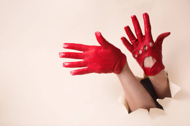 istock A woman's hands in a red leather gloves pushed through a hole 2188483688
