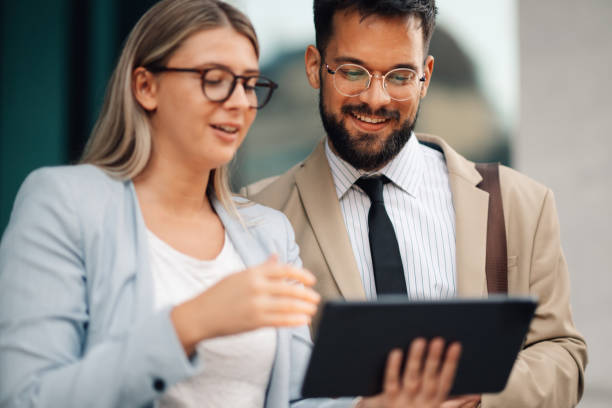 istock Two young business people discussing over digital tablet outside office building 2188483937