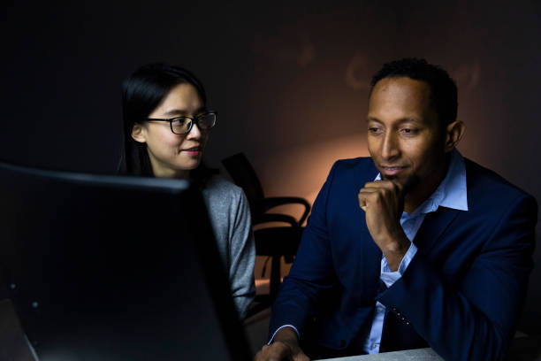 istock Businessman and businesswoman using a computer together during a late night at work 2188484754