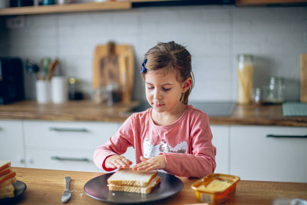 istock Happy girl making sandwiches in the kitchen 2188485119
